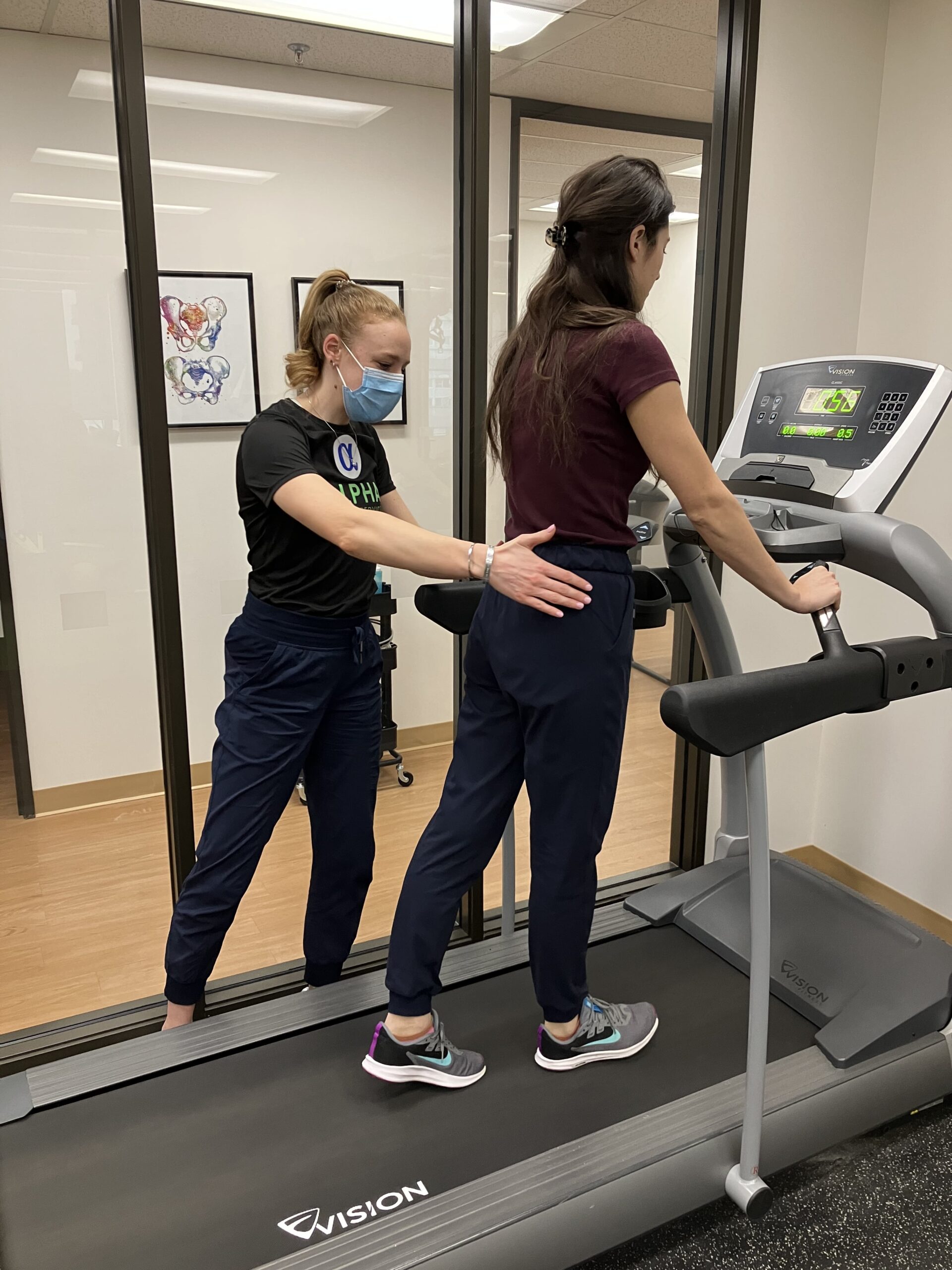 Physiotherapist working with female patient on treadmill